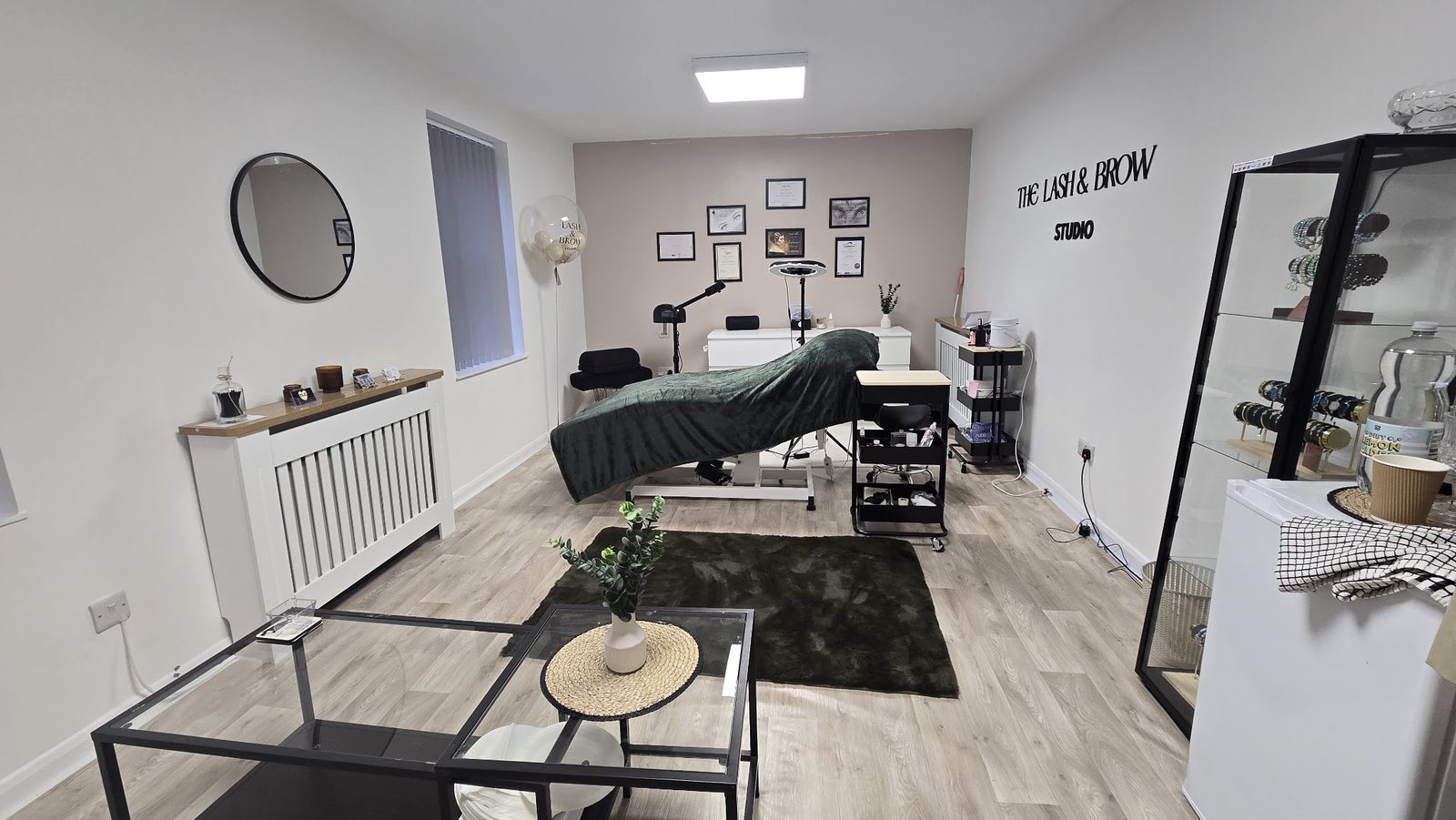Inside The Lash & Brow Studio: treatment bed, mirror, framed prints and the studio name on the wall