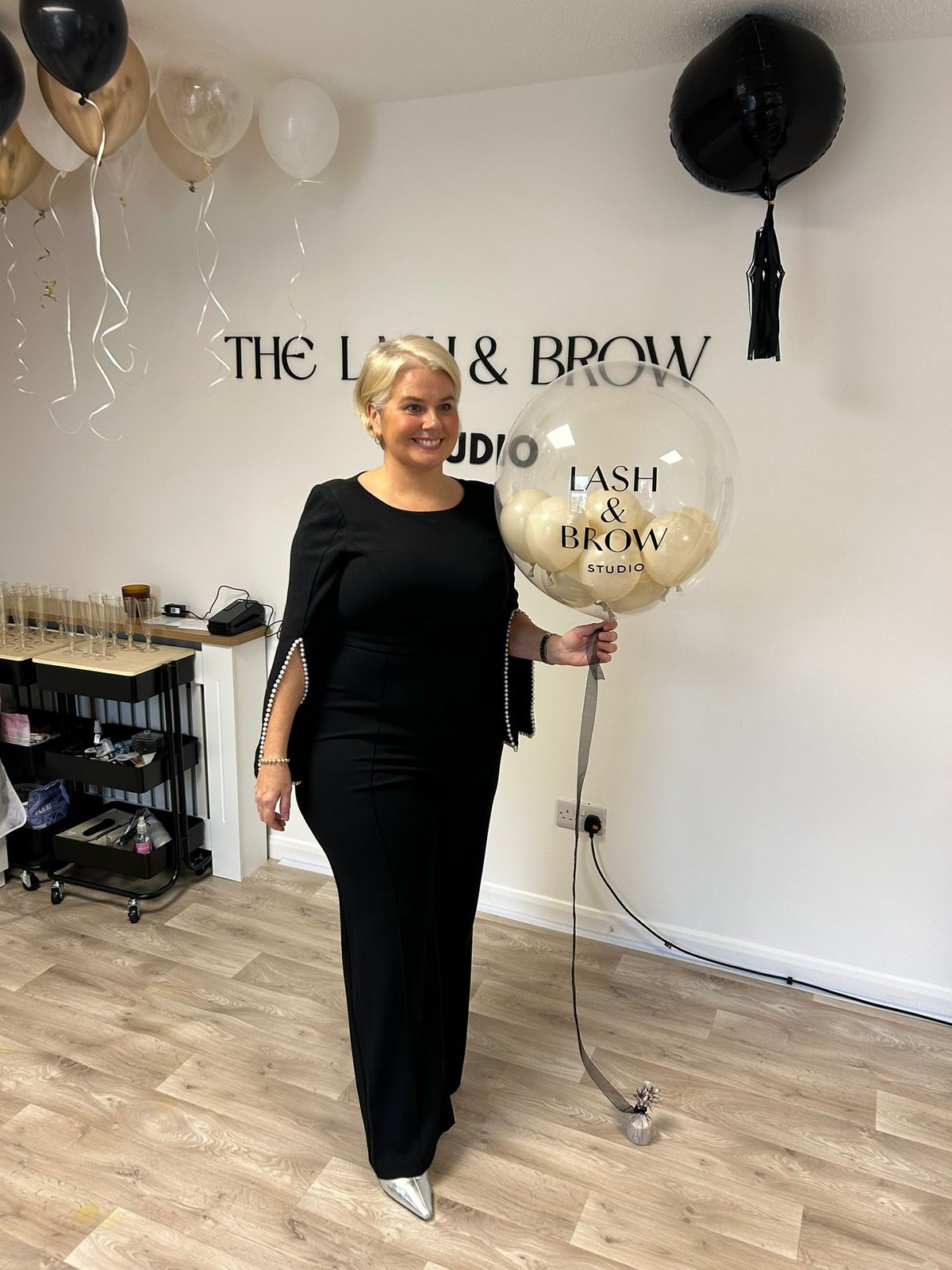 Sarah in the studio holding the Lash & Brow Studio balloon